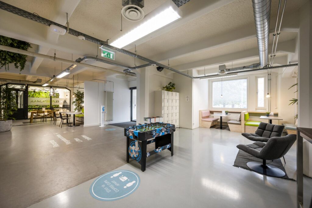 Modern common area on Van Diemenstraat with seating, lockers, a foosball table, and indoor greenery.